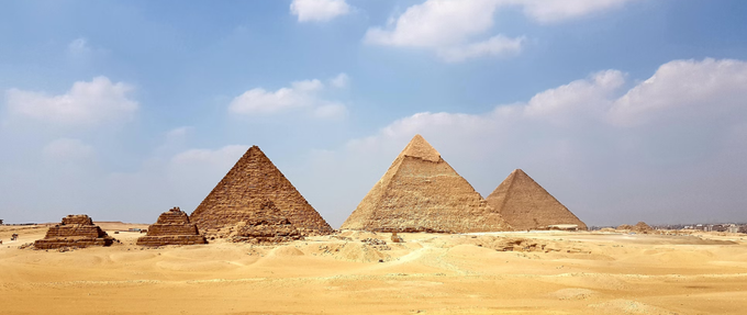 brown egyptian pyramids under cloudy blue sky