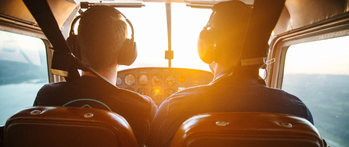 two pilots sitting next to each other in plane facing the sun