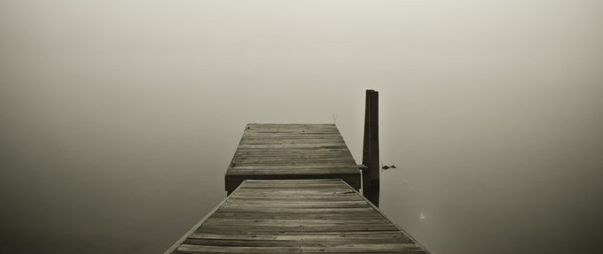 wooden deck overlooking a foggy pond